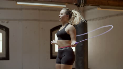 medium shot of focused caucasian woman jumping rope in gym