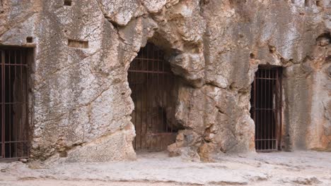entrada de una cueva rocosa con puerta barrada en atenas