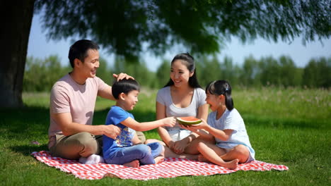 a happy family enjoys a picnic in a park, sharing watermelon on a sunny day