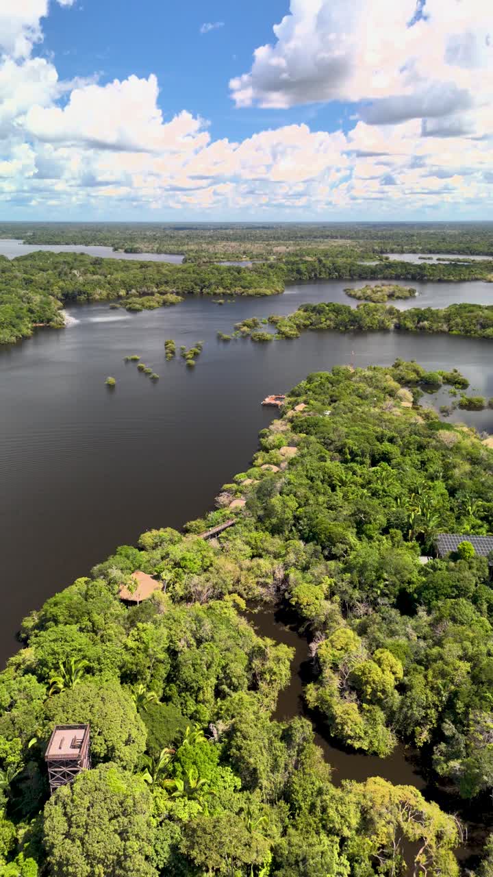 Drone ascending, panning right over Juma Rio Amazonas Brazil, river jungle lodge surrounded by lush green rainforest