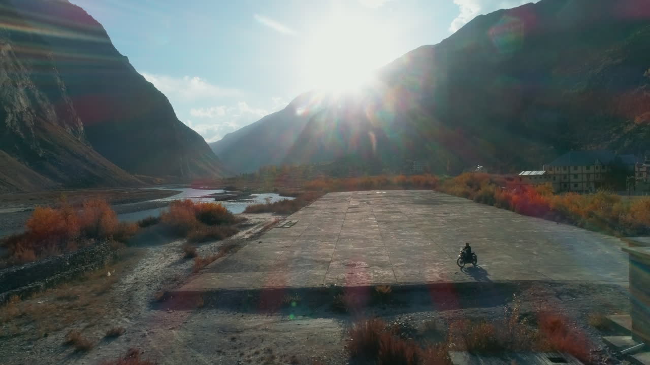 Extreme solo motor biker in a stunning himalaya mountain valley. Evening sunlight of autumn season. Aerial landscape of Lahaul Spiti, Asia