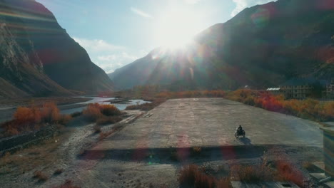 extreme solo motor biker in a stunning himalaya mountain valley. evening sunlight of autumn season. aerial landscape of lahaul spiti, asia