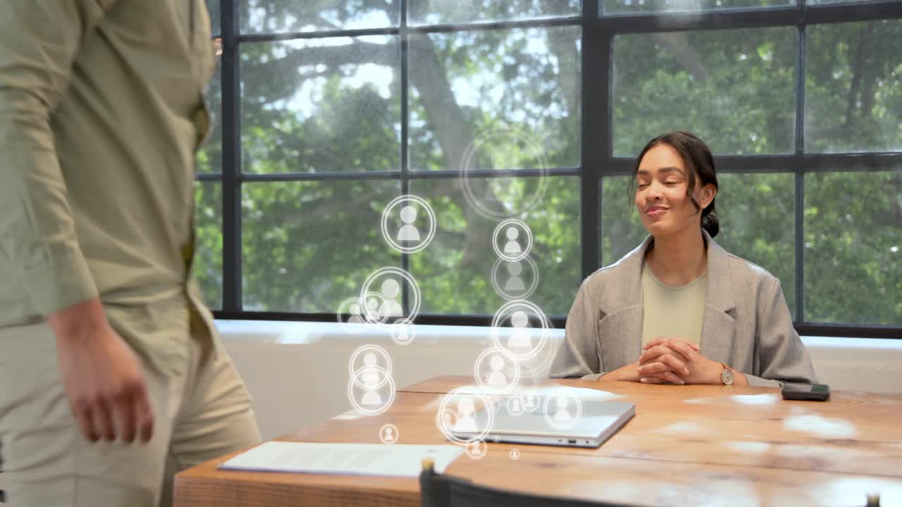 Woman watching man entering, arranging papers, laptop for business, animated icons overlaying table