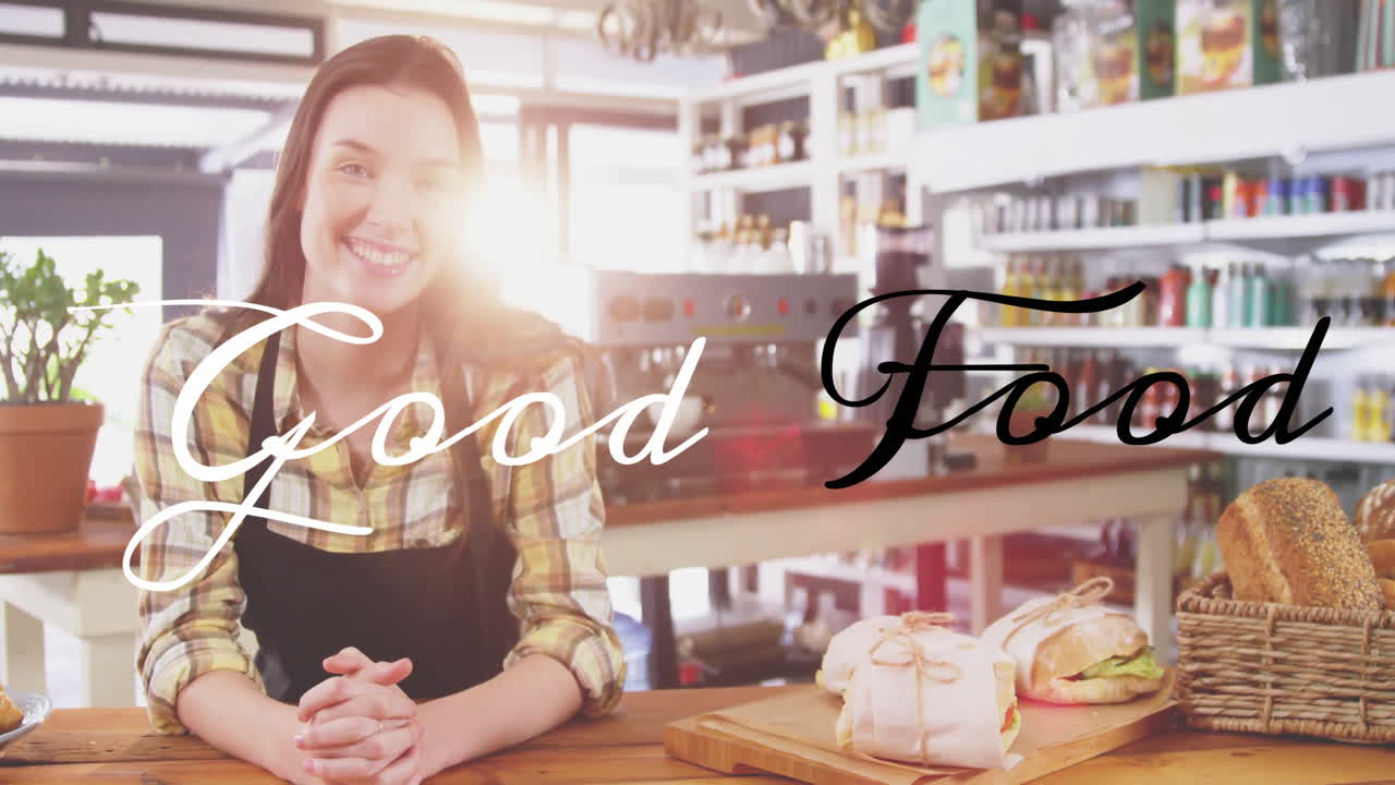 Smiling woman in kitchen with Good Food text animation over sandwiches on table