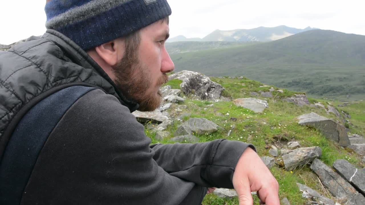 hombre blanco barbudo deprimido con escaleras de beanie en la cordillera desde la izquierda de cerca