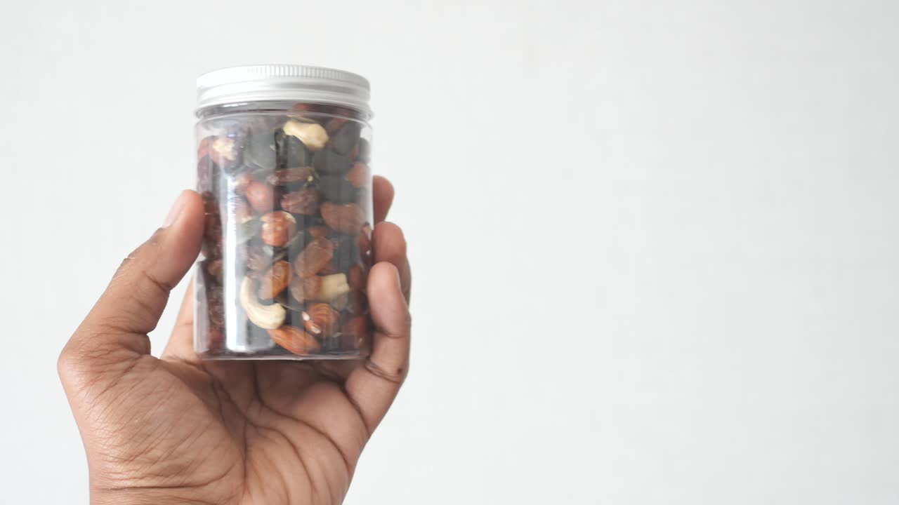 혼합 된 견과류의 항아리를 들고 있는 손