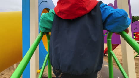 rear view of a kid running up to a slide ladder. happy active toddler goes up quickly and cheerfully.