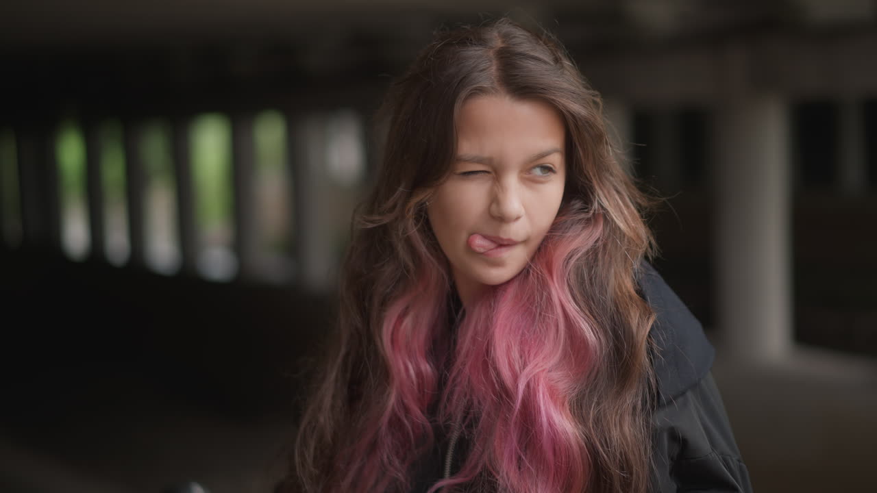Joyful rainwoman smile. Happy young woman smiles in rainy city. Woman with vibrant pink hair enjoys rainy weather openly. Cheerful young lady with pink streaked hair beams in rain under bridge