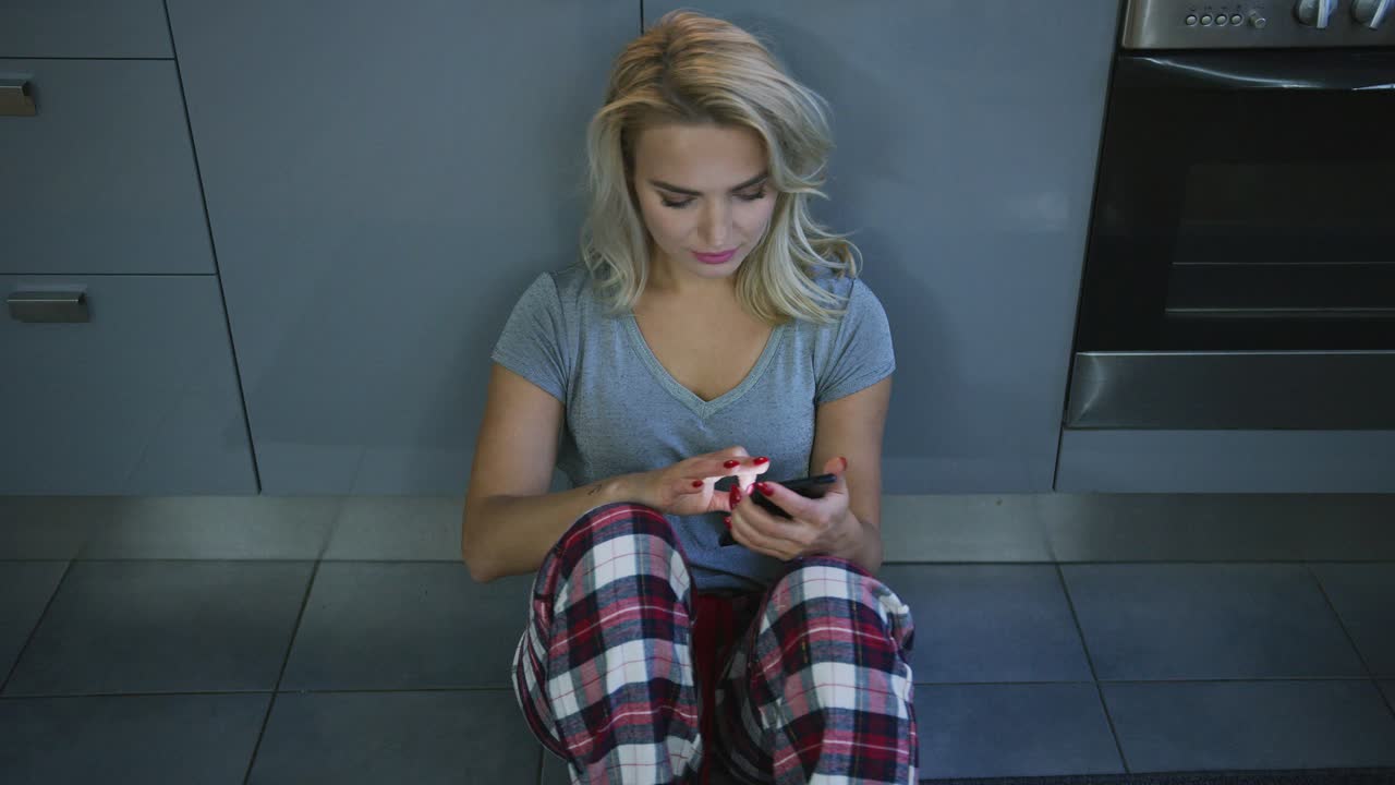 Charming woman with smartphone on kitchen floor