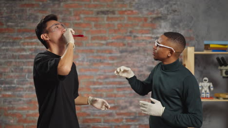 asian man tastes red liquid with old black friend in lab