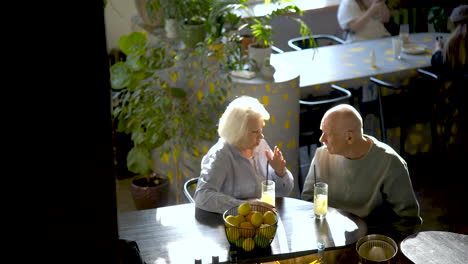 top view of a senior couple drinking limonade and talking while they are sitting in a bar at sunset