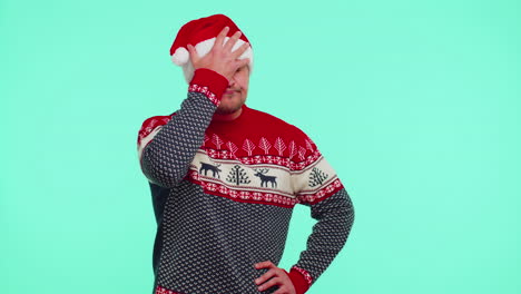 Upset-man-in-Christmas-red-sweater-making-face-palm-gesture,-feeling-bored,-disappointed,-bad-result
