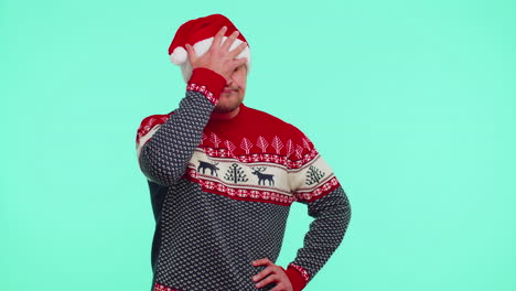 upset man in christmas red sweater making face palm gesture, feeling bored, disappointed, bad result