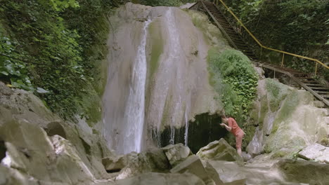 en una cascada en un bosque mujer