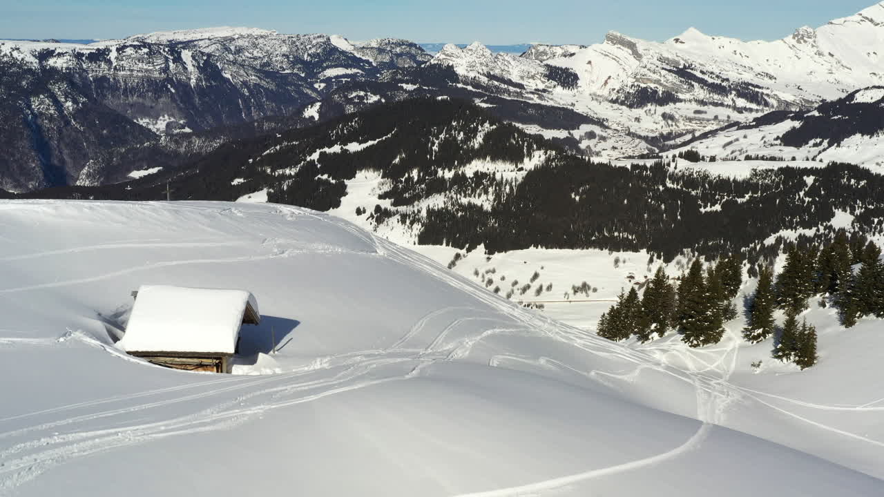 vista aérea volando hacia una pequeña cabaña de montaña cubierta de nieve en los alpes franceses en invierno