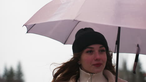 close shot of thoughtful girl running in light snowfall holding umbrella wearing knit cap brown shearling jacket, cold weather, serene atmosphere, winter scene, casual outdoor style, snowy day