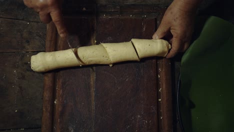 a overhead shot of a woman cutting paraguayan chipa to put in the oven and baked in a tatakua, a traditional paraguayan clay oven