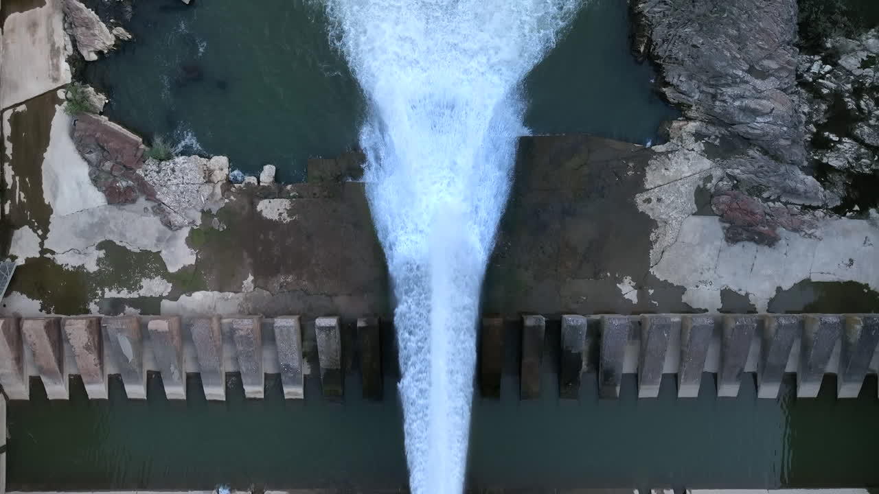 Dam pouring water to almost empty reservoir due to drought, aerial top down view