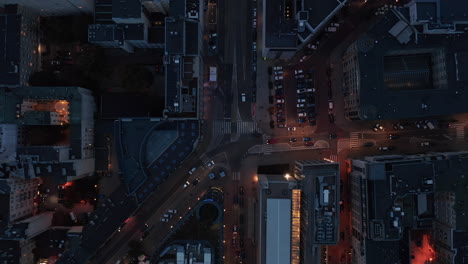 Aerial-birds-eye-overhead-top-down-panning-view-of-night-city.-Cars-driving-through-street-intersection.-Warsaw,-Poland