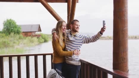 caucasian couple spending time at home together, taking a photo outside the cabin