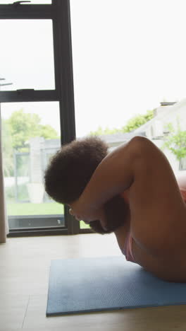 video vertical de una mujer biracial de tamaño grande haciendo ejercicio en casa