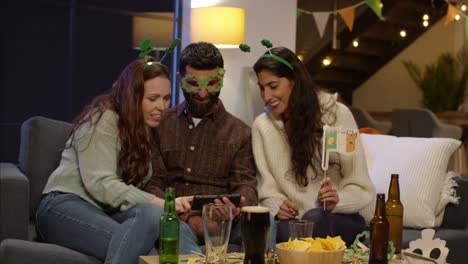 group of friends dressing up at home or in bar celebrating at st patrick's day party looking at photos on phone 3