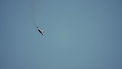 military jet fighter climbs vertically into the sky leaving trail of dark smoke