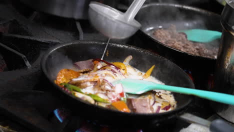 Ladle-pours-heaping-amount-of-creamy-white-milk-oversauted-vegetables-in-sizzling-skillet,-ladleful-of-sauce-simmers-after-being-slowly-added-to-hot-pan,-slow-motion-close-up-4K