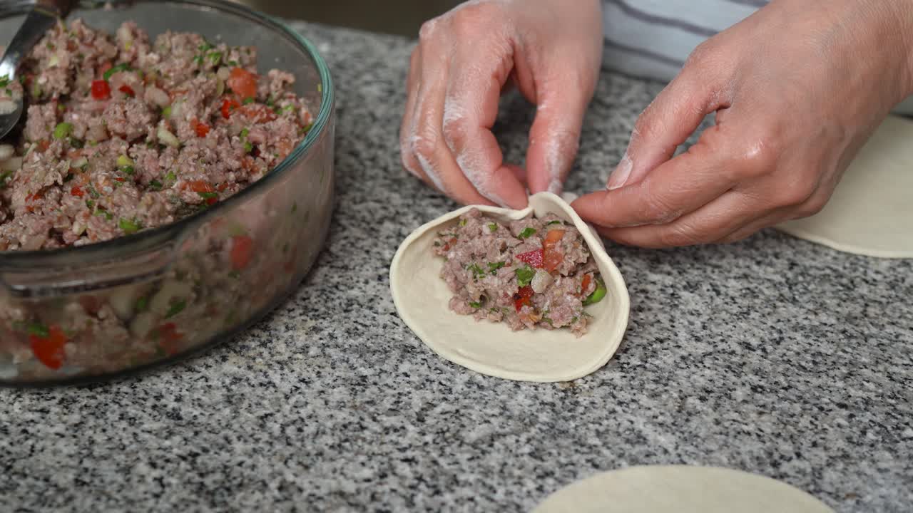 Woman filling and closing homemade fatayers