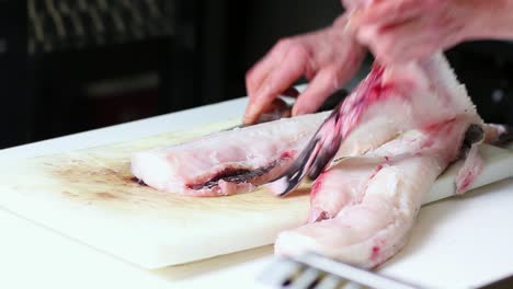 el chef está fileteando una merluza en un restaurante