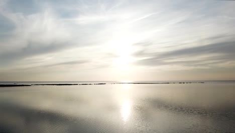 바람 없는 날 에스토니아에서 평평한 발트해 위로 빛나는 태양이 거울 같은 효과를 만들어냅니다.