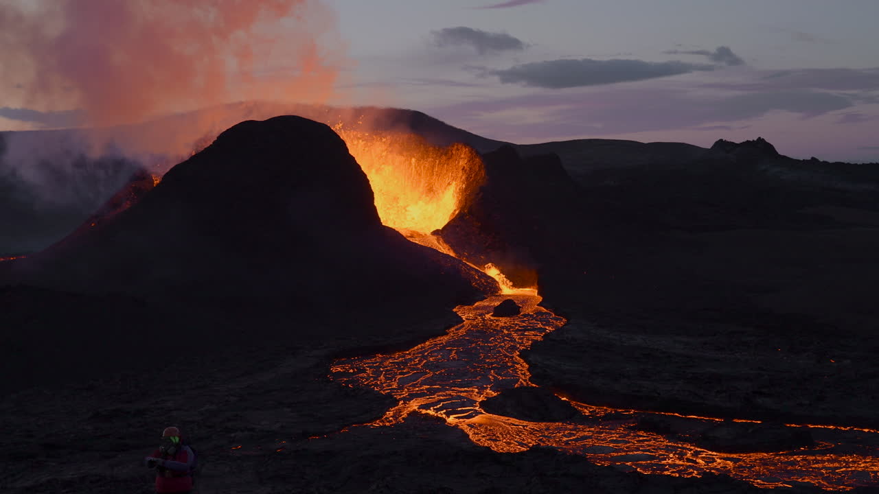 Ripresa aerea al rallentatore del vulcano Geldingadalir in eruzione con lava che scorre dopo il tramonto in Islanda.