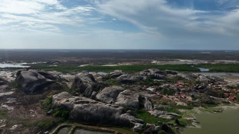 massive granite rock formations surround small village with red-roofed houses in chaval, ceará, brazil. aerial slow motion