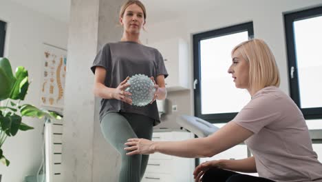 female physical therapist working with young woman using exercising ball.