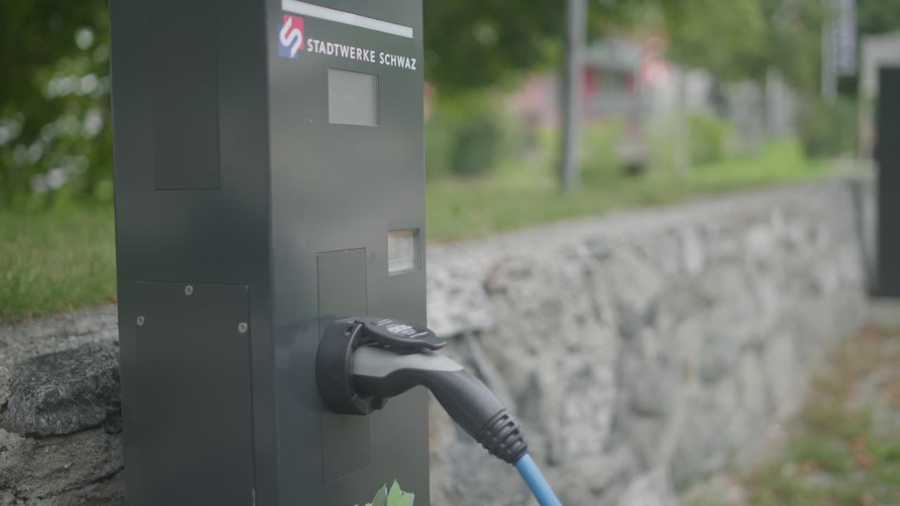 Close up of a modern electric car charger station with a charger being attached to a silver chaging station