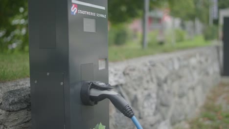 close up of a modern electric car charger station with a charger being attached to a silver chaging station