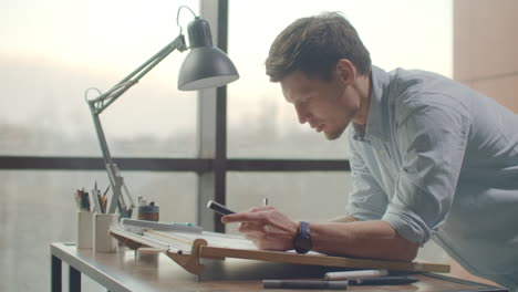 architect's desk: drawings tape measure ruler and other drawing tools. engineer works with drawings in a bright office close-up. insturments and office for designer. male hands draw with a pencil.