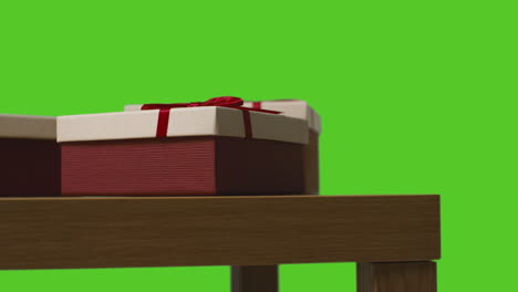 Close-Up-Of-Gift-Wrapped-Presents-On-Table-Shot-Against-Green-Screen