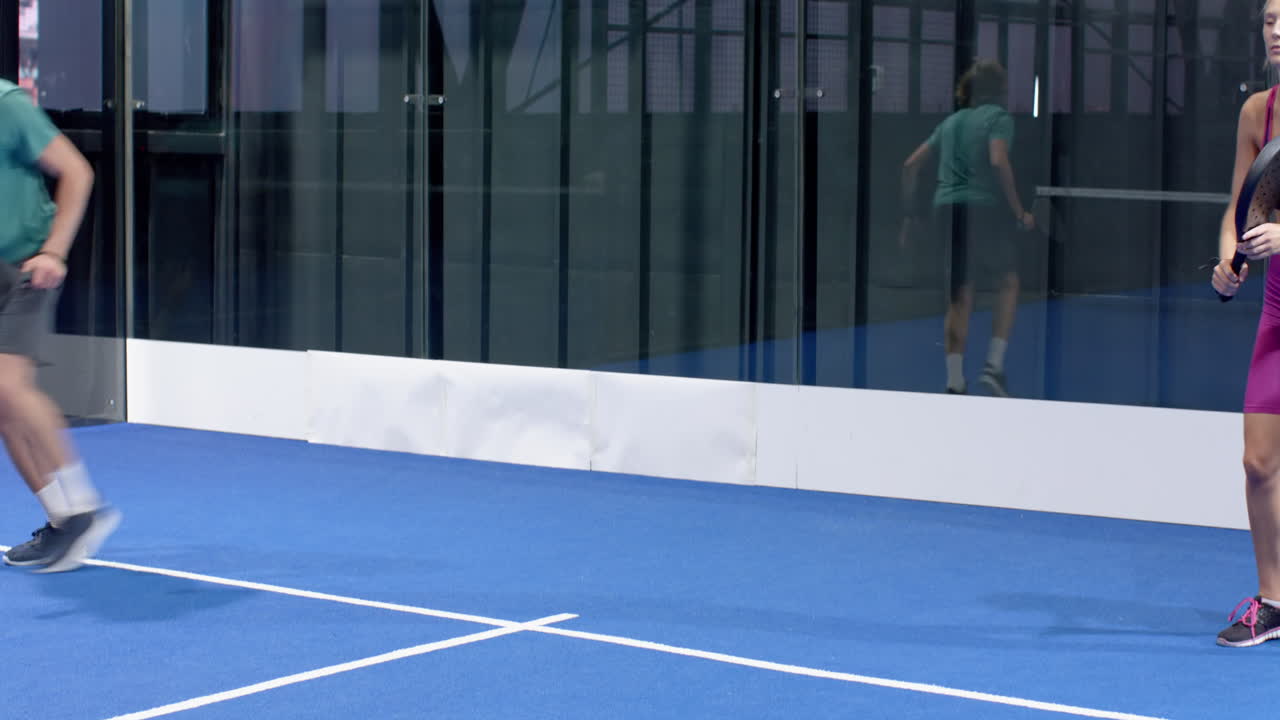Young man playing padel tennis on blue indoor court, focused and ready for action