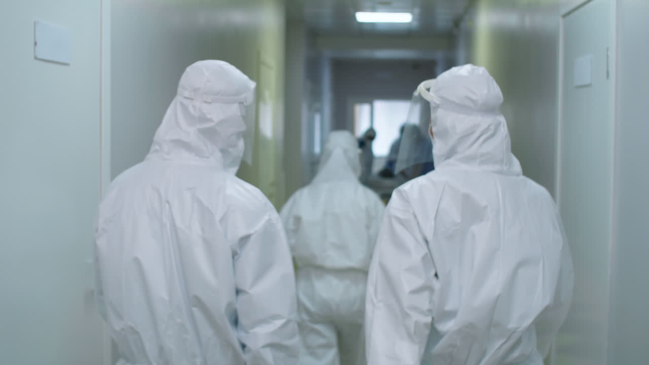 Medici con indumenti protettivi che camminano lungo il corridoio dell'ospedale