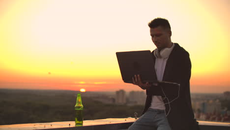 hipster man with a laptop on the edge of the roof. freelancer at work. wireless mobile internet. he works on the internet.