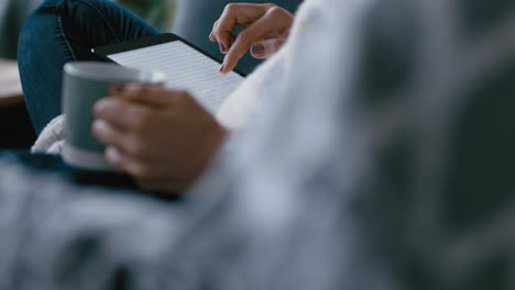 Cerrar-Las-Manos-De-Una-Mujer-Usando-Una-Tableta-Navegando-Por-Las-Redes-Sociales-Revisando-Correos-Electrónicos-En-Un-Dispositivo-Móvil-Con-Pantalla-Táctil-Relajándose-En-Casa-Tomando-Café