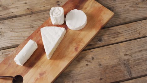 video overhead shot of assorted soft cheeses on chopping board, on wooden table with copy space