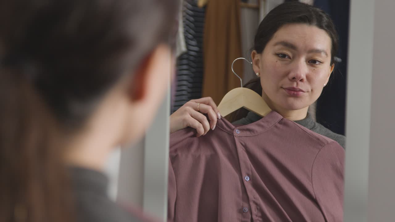 거울에 비친 취업 면접을 위해 집에서 옷을 고르는 젊은 여성