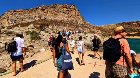 tourists walking on cliffside path to a beach