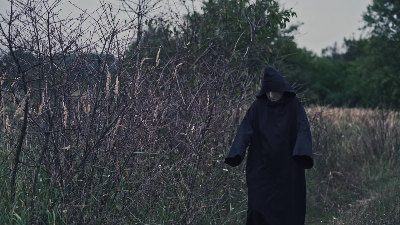 Ghost wandering in nature. Hooded ghostly figure in countryside field