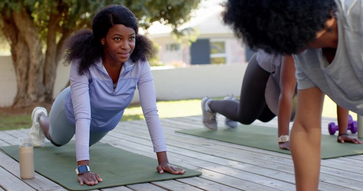 Diverse women reacting to coach cue, African woman lifting cobra into plank, pressing on deck mats