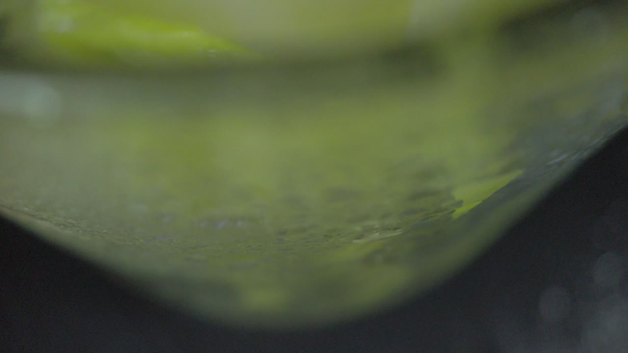Close look of a glass cup full of green mango and  crushed ice from the bottom to the top