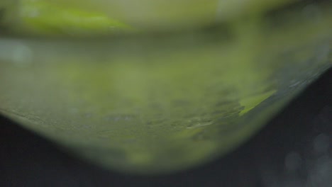 close look of a glass cup full of green mango and  crushed ice from the bottom to the top