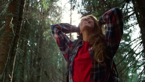 Joyful-woman-taking-break-during-hike-in-woods.-Smiling-girl-standing-in-forest